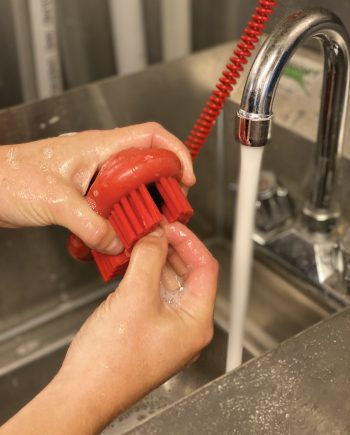 Hand and nail brush being used at a sink